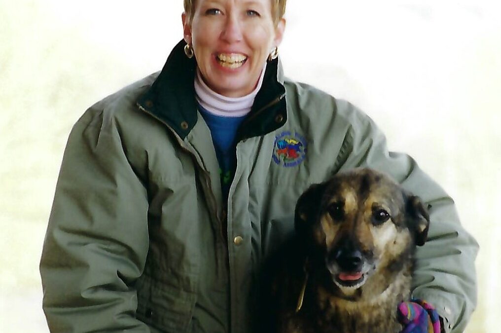 A photo of HTA Founder Carol Komitor from 1999 with her arm around a German Shepherd mix breed dog.